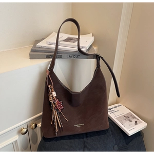 Detailed view of dark brown suede hobo bag with fringe tassel and leather texture