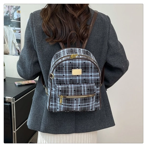 Détail du sac à dos vintage à carreaux avec tissu bleu-gris et accents en cuir brun