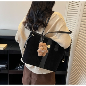 Detail view of black suede tote bag featuring golden square hardware and brown bear charm