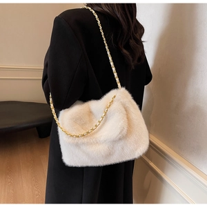 Détail du sac bandoulière en peluche crème avec une chaîne en métal doré chic