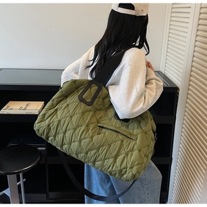 Detail of olive green quilted tote bag with diamond stitching and front zipper pocket