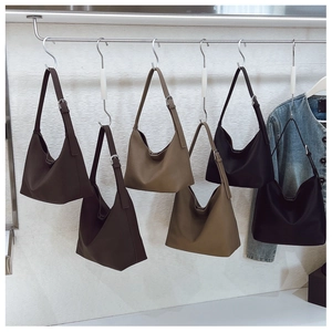 Detailed view of adjustable shoulder straps on minimalist leather underarm bags in three colors