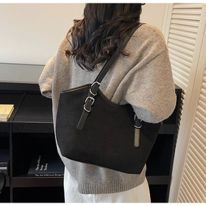 Vista dettagliata della borsa tote nera in camoscio con fibbia argentata sulla modella