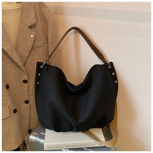 Detail of black canvas tote bag with brown leather handles and silver decorative rivets