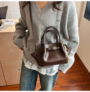 Detail of a dark brown vintage handbag featuring a beaded charm in a cozy indoor setting