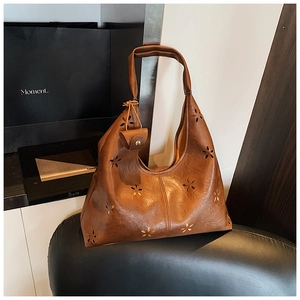 Détail d'un sac Hobo marron avec motifs floraux découpés au laser et une petite pochette