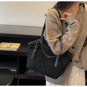 Dettaglio della borsa tote in pelle scamosciata nera con manici in pelle e fibbia in metallo