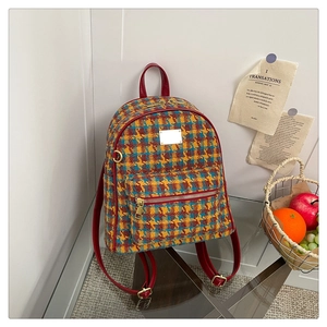 Détail du sac à dos vintage à carreaux montrant la texture tweed et bretelles rouges