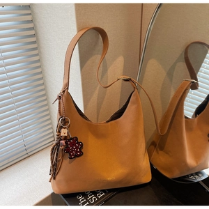 Close-up of brown hobo bucket bag with leopard print bear charm and tassel detail