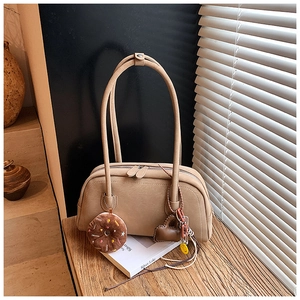 Detail view of khaki retro boston bag with cute charms on a wooden table setup
