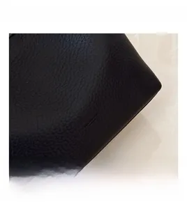 Close-up of premium black lychee pattern leather texture with embossed logo detail