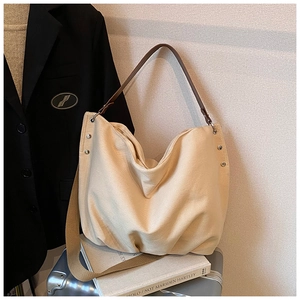 Detail of beige canvas hobo tote with brown leather strap on a silver suitcase