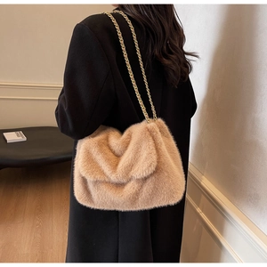 Détail rapproché de la texture pelucheuse et de la chaîne dorée d'un sac porté épaule brun