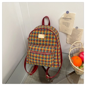 Détail du sac à dos vintage en pied-de-poule avec bordure en cuir rouge et métal doré