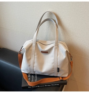 Detail of canvas tote bag with adjustable orange strap on a leather sofa