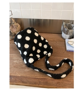 Gros plan d'un sac seau en peluche à pois noirs et blancs sur une surface en bois
