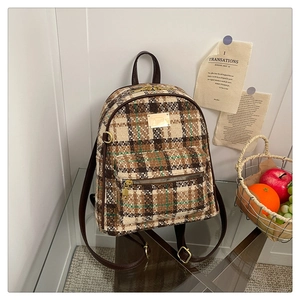Détail d'un sac à dos vintage à carreaux avec finitions en cuir marron et boucles dorées