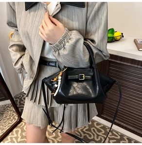 Detail of black leather handbag featuring a vintage buckle and colorful beaded charm strap
