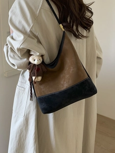 Borsa a secchiello bicolore marrone e nera con un grazioso ciondolo a forma di orso