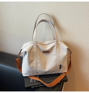 Detail of off-white canvas tote bag with a brown wide strap and premium leather brand logo