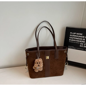 Detail of retro brown suede tote bag with leather trim and plush bear charm