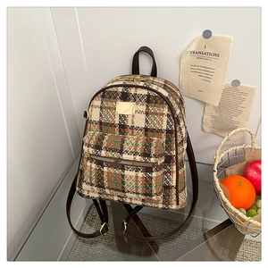 Détail du sac à dos vintage à carreaux avec garniture en cuir brun et fermetures éclair dorées