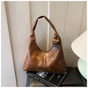Gros plan du sac hobo marron avec découpes laser florales sur un livre