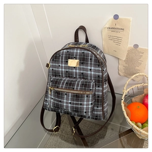 Détail du sac à dos vintage à carreaux bleus avec bordure en cuir brun et finitions dorées