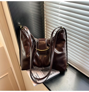 Detail of dark chocolate glossy leather tote with elegant gold crescent metal buckle