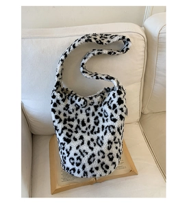Détail d'un sac cabas en peluche à motif léopard noir et blanc sur canapé blanc