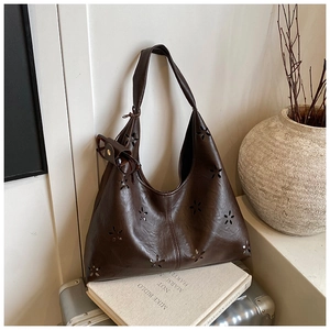 Détail du sac hobo marron foncé avec motifs floraux découpés au laser et mini pochette