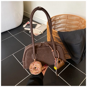 Detail of dark brown Boston bag with contrast stitching and plush donut charms