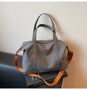 Close-up of canvas tote bag featuring brown adjustable strap and brand tag detail