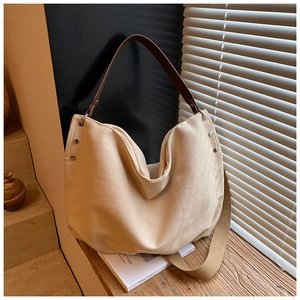 Detail shot of beige canvas tote bag with brown leather handles on a wooden table