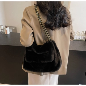 Détail d'un sac à bandoulière en fausse fourrure noire avec chaîne dorée sur un blazer