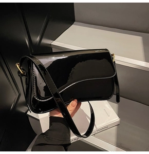 Detail of black patent leather bag with mirror finish and gold metal buckle