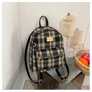 Détail d'un sac à dos en tweed à carreaux noirs et blancs avec garnitures dorées et cuir