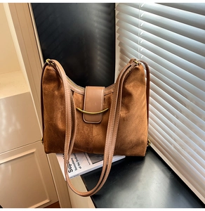 Detail of caramel suede hobo bag with gold crescent hardware and leather strap