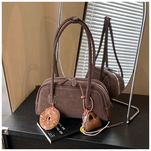 Detail of brown suede Boston bag with silver double zippers, charms and contrast stitching