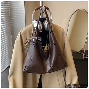 Détail du sac cabas en cuir marron foncé avec motifs floraux ajourés élégants et accessoire