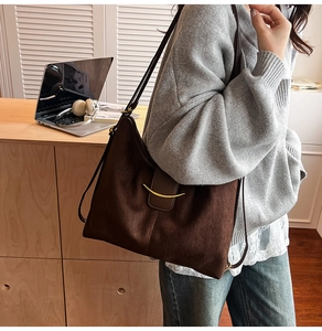 Detail view of large dark brown tote bag with crescent gold hardware and leather stitching