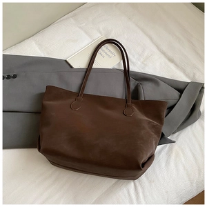 Detail of minimalist dark brown large capacity tote bag on soft white fabric background