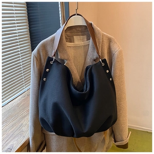 Detail of canvas tote with brown leather strap, silver rivets and oversized hobo silhouette