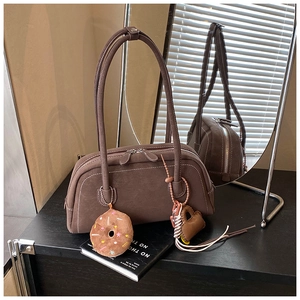Detail view of brown vintage Boston bag with white stitching and plush donut charm