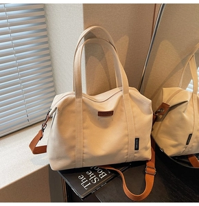 Detail of cream canvas tote bag with brown woven straps and adjustable crossbody belt