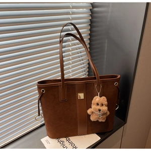 Detail of dark brown suede tote bag with golden ring drawstrings and cute puppy charm