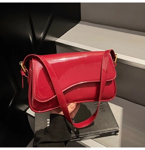 Detail of red patent leather shoulder bag with glossy finish and gold metal hardware