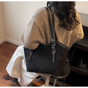 Dettaglio delle fibbie in argento regolabili sulla borsa tote nera in pelle scamosciata