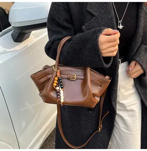 Close-up of dark brown wrinkled PU leather handbag with decorative wooden beads and metal buckle