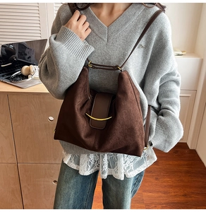 Detail of a dark brown suede Hobo bag featuring a gold crescent metal buckle and leather strap